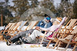 Couple in love at mountains in winter laughing and relax in sunbed