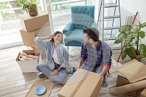 Couple packing their possessions into cardboard boxes while moving house