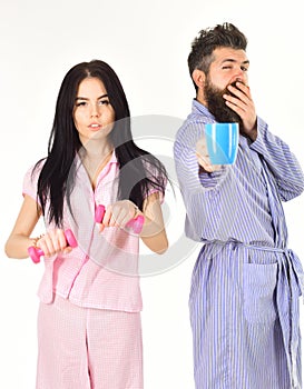 Couple in love in pajama, bathrobe stand isolated on white background. Alternative lifestyle concept. Girl with dumbbell