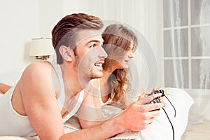 Couple in love playing video games in bedroom, side view