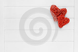 Couple of love red pedig rattan hearts on wooden light background