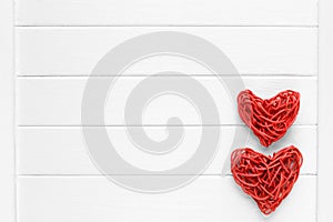 Couple of love red pedig rattan hearts on wooden light background