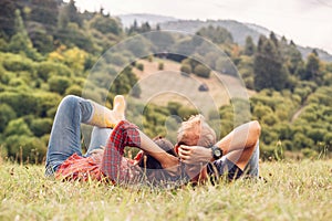 Couple in love rest on green hill in country side