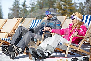 Couple in love resting from skiing in sun lounger
