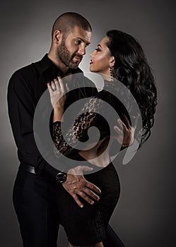 Couple in Love. Romantic Fashion Woman in Black Dress and Man dancing. Models Portrait Embracing and Looking at Each other