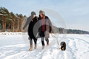 Couple in love running on winter beach with puppy dog