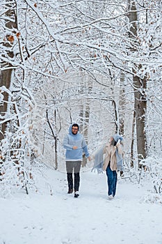 Couple in love running through a winter forest on a snowy day