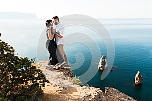 Couple in love at sea hugging on the edge of the cliff