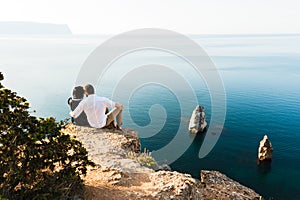 Couple in love at sea hugging on the edge of the cliff