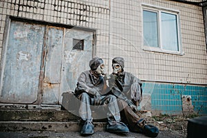 Couple in love sits in NBC protective suits and gas masks near building
