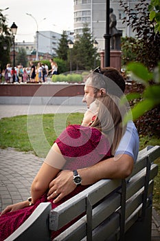 Couple in love is sitting on a bench. Man and woman enjoy each other`s conversation in the summer park
