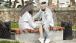 Couple in love sitting on a bench in a park looking each other