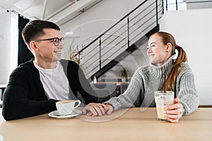 Couple in love sitting in cafe looking at each other and holding hands