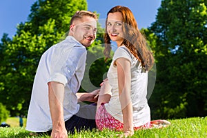 Couple in love sitting on park lawn