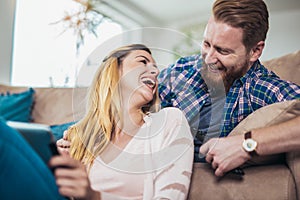 Couple sitting on the sofa and using digital tablet, having fun