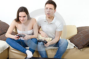 Couple in love on sofa sitting and playing video games in living