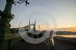 Couple in love is standing on the liberty bridge over the river Danube in Budapest. Sunrise in the big city. Dark silhouettes of