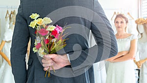 a couple love standing in wedding studio with a man surprise give bouquet of flowers from his hand to bride