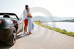 Couple in love stands near the cabriolet car on the picturesque