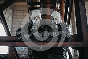 Couple in love stands under bridge in NBC protective suits and gas masks