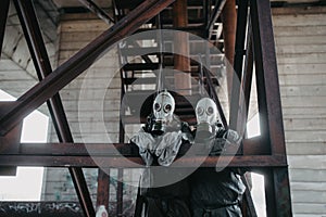 Couple in love stands under bridge in NBC protective suits and gas masks