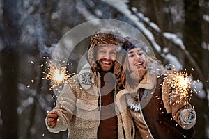 Couple Love Story in Snow Forest Kissing and Holding Sparklers. Couple in Winter Nature. Couple Celebrating. Valentine's