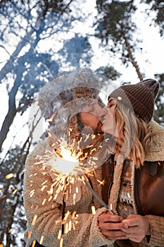 Couple Love Story in Snow Forest Kissing and Holding Sparklers. Couple in Winter Nature. Couple Celebrating. Valentine& x27;s