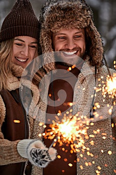 Couple Love Story in Snow Forest Kissing and Holding Sparklers. Couple in Winter Nature. Couple Celebrating. Valentine's