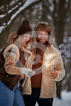 Couple Love Story in Snow Forest Kissing and Holding Sparklers. Couple in Winter Nature. Couple Celebrating. Valentine's