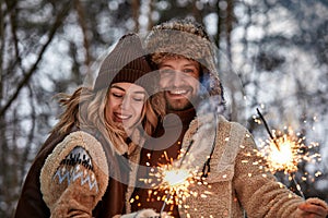 Couple Love Story in Snow Forest Kissing and Holding Sparklers. Couple in Winter Nature. Couple Celebrating. Valentine's