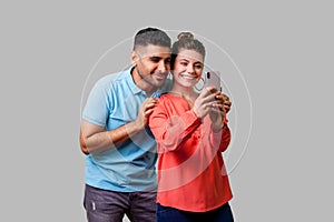 Couple in love taking picture together! Portrait of happy beautiful woman doing selfie with boyfriend. isolated on gray background