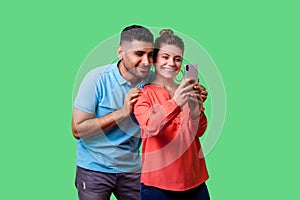 Couple in love taking picture together! Portrait of happy beautiful woman doing selfie with boyfriend. isolated on green