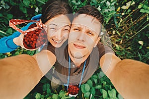 Couple in love taking self-portrait in summer raspberry garden