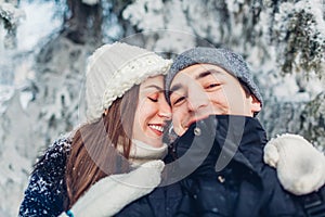 Couple in love taking selfie and hugging in winter forest. Young happy people having fun. Valentine`s day