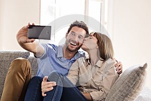 Couple in love taking a selfie with a mobile phone. She kisses him photo