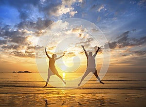 Couple in love to jump up on the beach during a stunning sunset. Happiness.