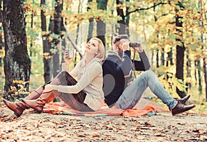 Couple in love tourists relaxing picnic blanket. Man with binoculars and woman with metal mug enjoy nature park. Park