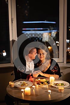 couple in love for valentine's day, candlelight dinner, red wine on a date, a man holding a woman's hand at a festive