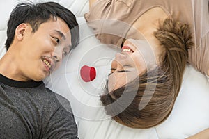 Couple, Love and Valentine`s Day Concept. Portrait of two smiling asian man and woman looking on each other face and laying on be