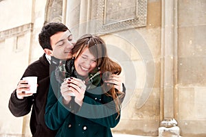 Couple in love walk in snow city in winter, hugging, kissing, have fun and fool and drink hot tea