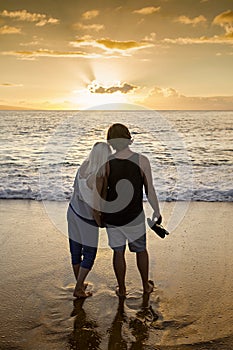 Couple in love walking along the beach together at sunset