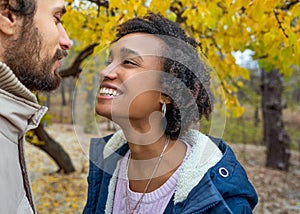 Couple in love are walking in the autumn park. Afroamerican girl with a European