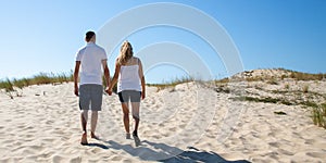 Couple in love walking back view on the beach in web template banner panorama