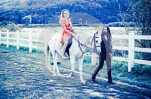 Couple in love walking with horse on countryside. Romantic love story of sensual couple. Woman riding grey arabian horse