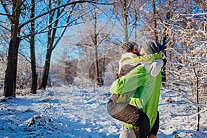 Couple in love walking and hugging in winter forest. Man holding girlfriend and kissing. Young people having fun