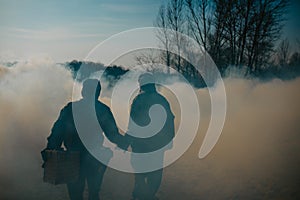 Couple in love walks in NBC protective suits and gas masks on smoke background