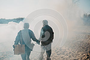 Couple in love walks in NBC protective suits and gas masks on smoke background