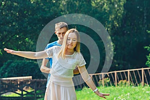 A couple in love walks in a summer park by the lake.A man supports his woman.