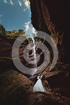 Couple in love on a waterfall. Honeymoon trip. Happy couple in the mountains, high angle view of the entire mountain