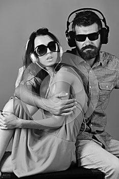 Couple in love wears headphones and sunglasses. Man with beard and girl hug on red background. Technologies, party and